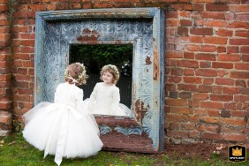 At Gaynes Park in Essex, a flower girl admires her reflection in a giant mirror. The sweet, candid images captures her joy on the wedding day.